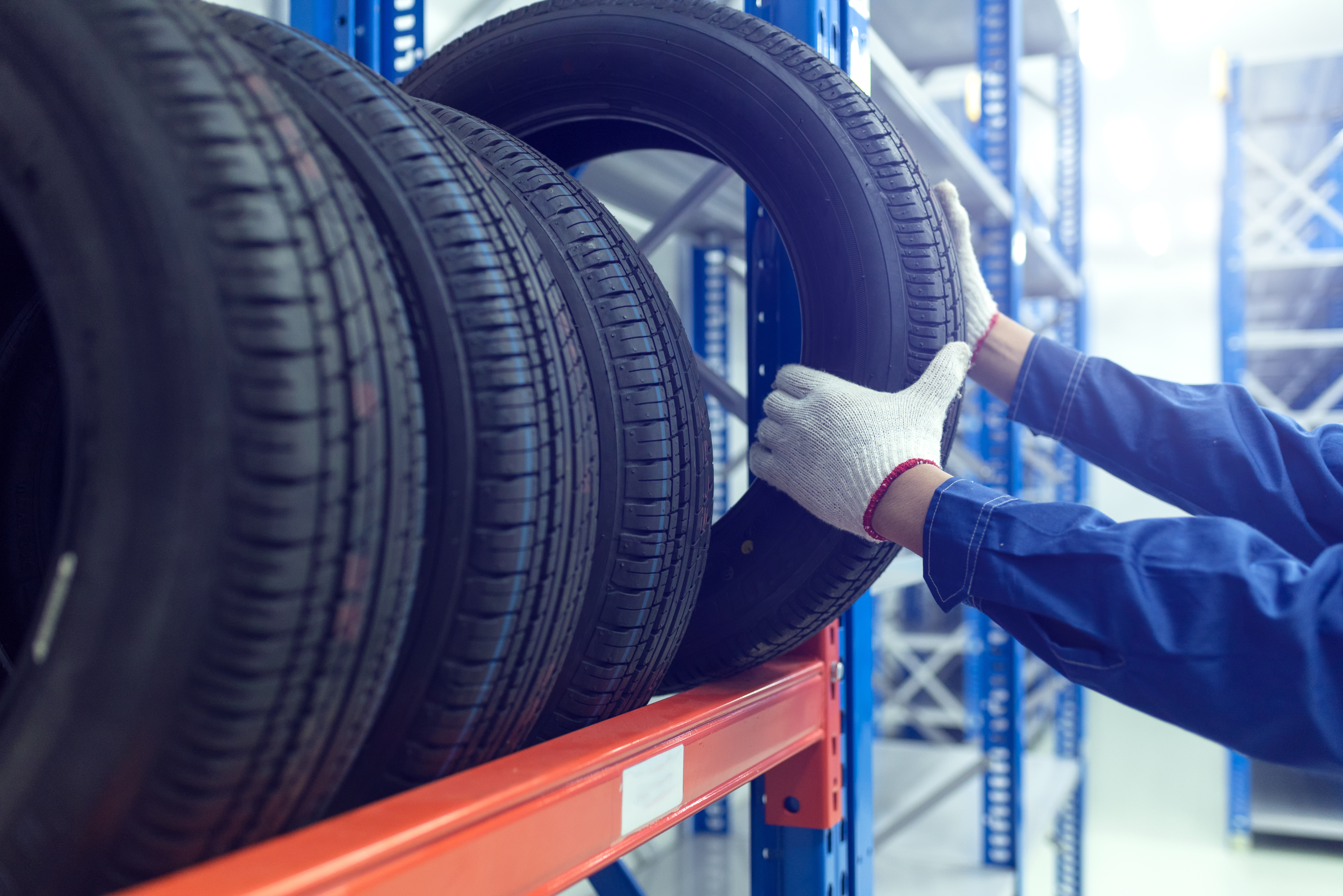 tires on rack with mechanic grabbing a tire